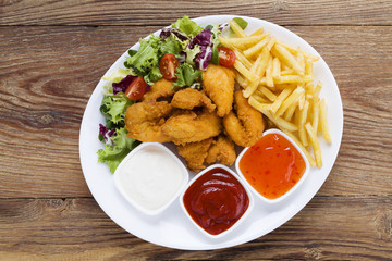 Nuggets and chips on a plate served with dip and salads