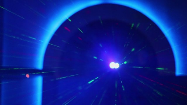 Laser emits rays under blue arch covered by smoke in night club