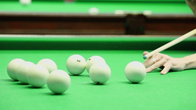 Man supports cue by hand and hit billiard ball