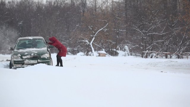 Woman helps to release car from snow trap on country road