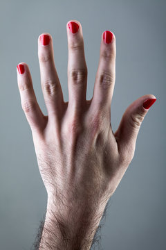 Man's Hand with Red Nail Polish on Gray Background