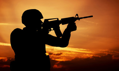 Soldier shooting with his weapon, rifle at sunset. War