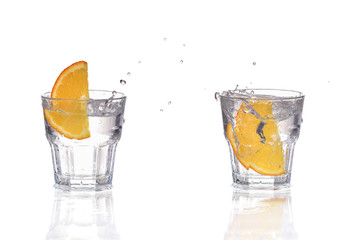 Orange or lemon slice fall in glass with water and make splash