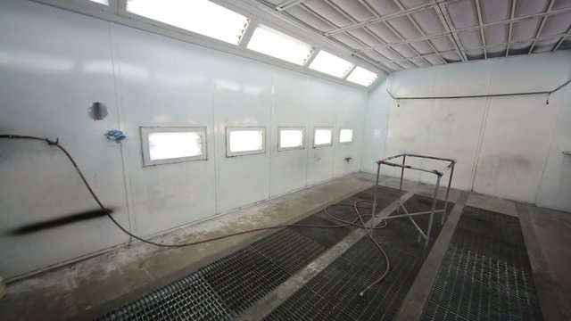 Small empty paint-spraying booth with grey metal walls for cars