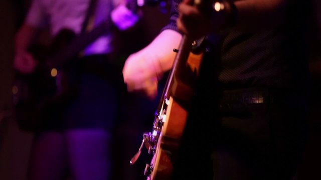 Young man and woman play on guitars on stage during concert