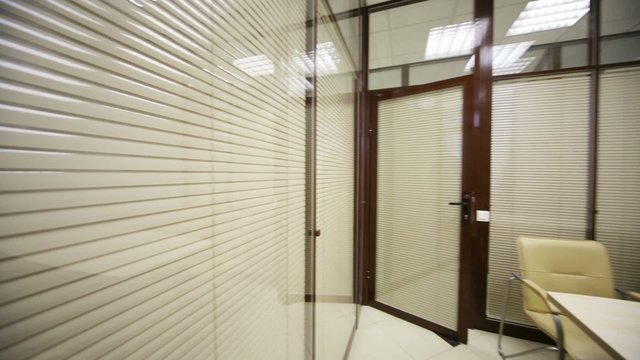 table and chairs in small lit meeting room with louvers on wall