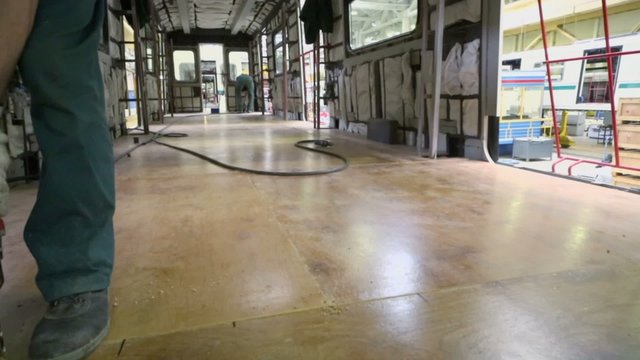 Worker drills wooden floor during assemblage of train
