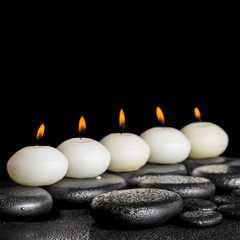 spa still life of row white candles on black zen stones backgrou