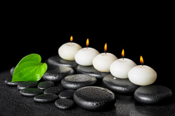 Obraz na płótnie Canvas spa still life of row white candles and green leaf on black zen