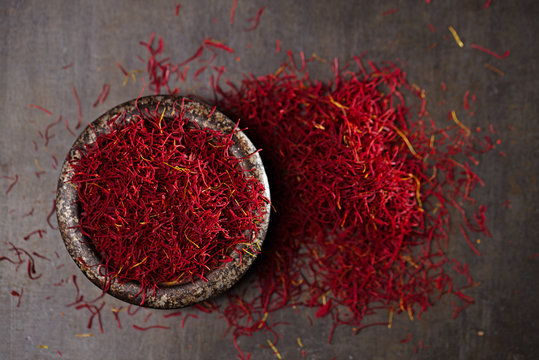 saffron spice threads and powder  in vintage iron dish