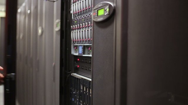 Engineer unlocks door of server rack with hard drives
