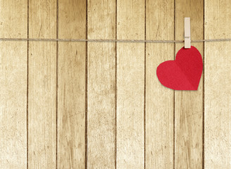 Red fabric heart hanging on clothesline over vintage wood