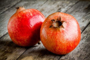two ripe pomegranate on a wooden background