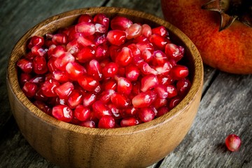 ruby pomegranate grains closeup in a wooden bowl on a table