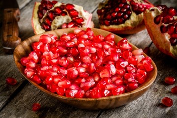 ruby pomegranate grains closeup in a wooden bowl on a table