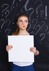 Young girl with question mark holding a blank on  gray