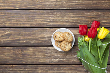Tulips and cookies on a wooden table.