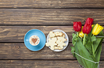 Cup of cappuccino with heart shape and bouquet of tulips with co