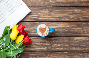 Cup of cappuccino with heart shape and computer