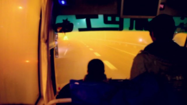 Silhouette of driver and passenger rides in bus by motorway covered by fog at night