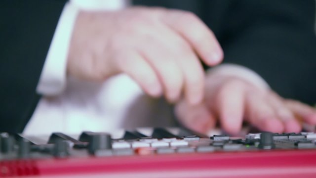 Man in suit plays on digital piano, closeup view