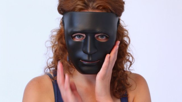 red-haired woman in black mask feels her hands and turns in profile close up