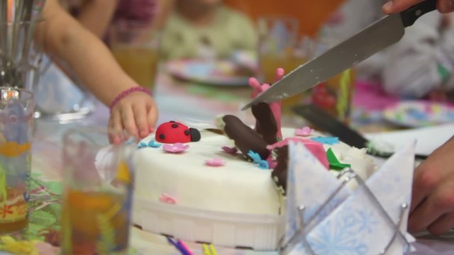 Mans hand cuts cake by knife on holiday table
