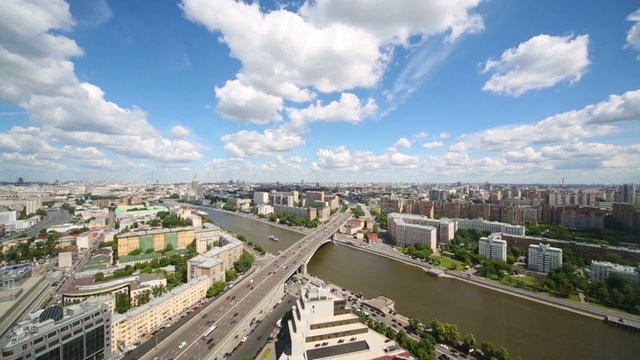Wide cityscape view with many buildings, river, sky and clouds.