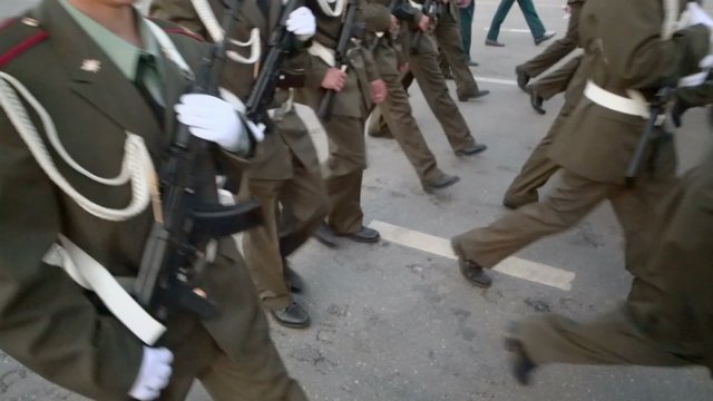 Soldiers in tunics marching with rifles during parade