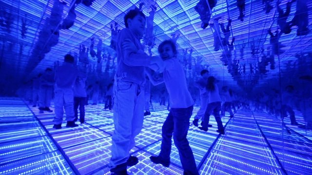 Boy and girl have fun in a mirrored room with blue lights