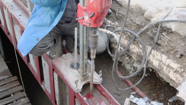 Worker drills metalware by huge drilling tool