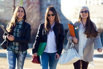 Three students girls walking in the campus of university.