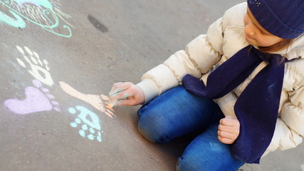 Girl drawing with colored chalk on the pavement