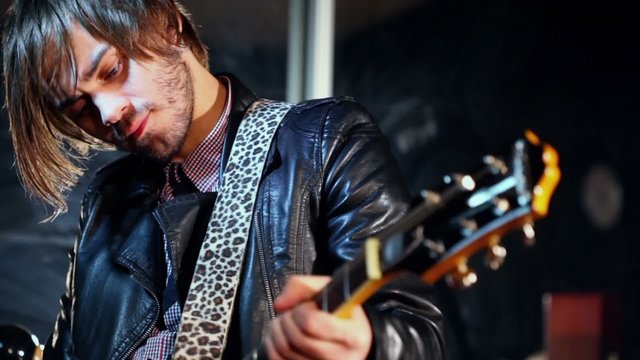 Guitarist in black leather jacket plays on electroguitar