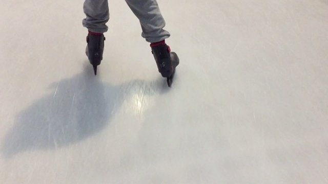 Child practicing ice skating, view from behind.