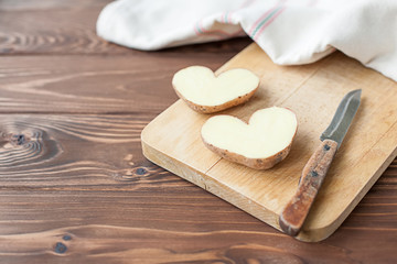 Fototapeta na wymiar Heart shaped potato on the plank with knife