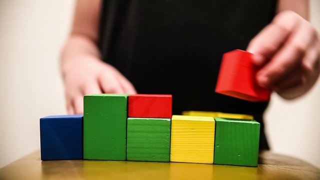 teenager boy builds a tower  of bricks blocks play a major hand