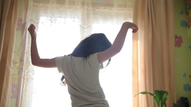 Teen girl stretches awake standing at window silhouette spin