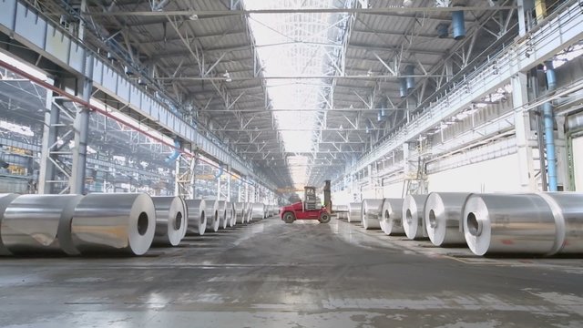 Loader machine drives by storage of aluminum rolls at workshop