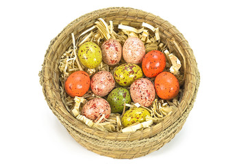 Colorful painted easter eggs in brown basket isolated on white