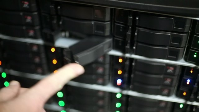 Hand closes doors of boxes for hard drives at data server rack