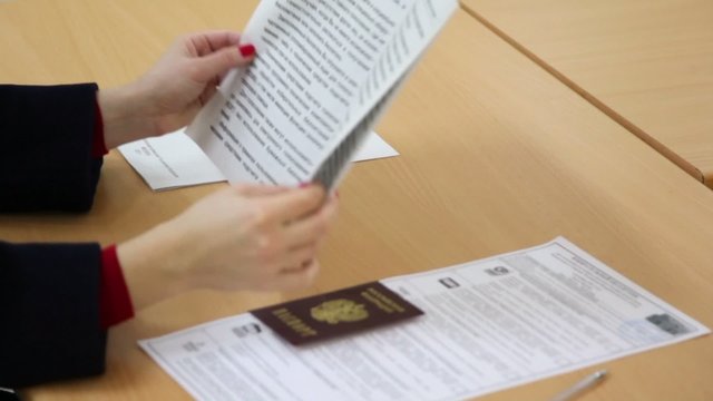 Woman turn page of voting rules booklet with passport