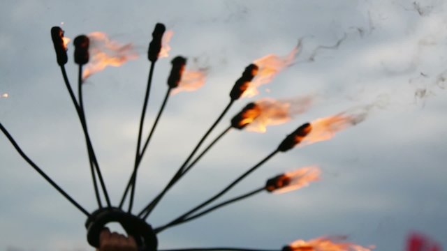 Many burning and smoking torches in hand at background of sky