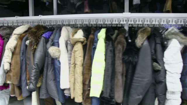 Many winter clothes hang at conveyor which moves