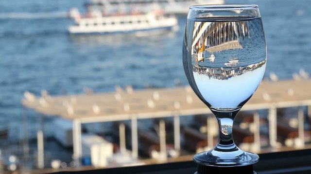 Reflection of river woth sailing ships in wineglass at sunny day