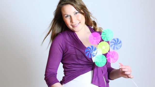 Young pregnant woman playing with a wind toy posing