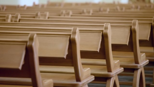 Row of wooden benches in cathedral, (closeup view in motion)