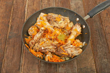 Fried chicken in the pan on a wooden background