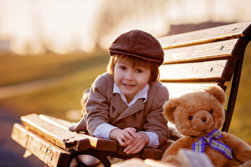 Adorable little boy with his teddy bear friend in the park