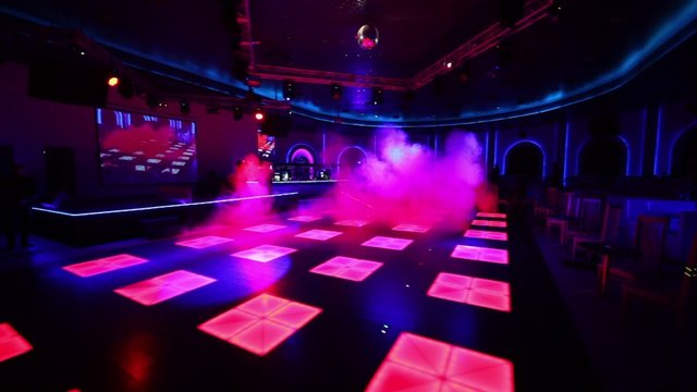 Fog covers dance floor of nightclub with illumination 